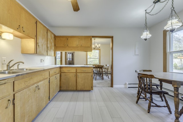 kitchen featuring pendant lighting, light countertops, a sink, light wood-type flooring, and a peninsula