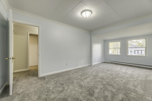 carpeted spare room featuring a baseboard heating unit, crown molding, and baseboards