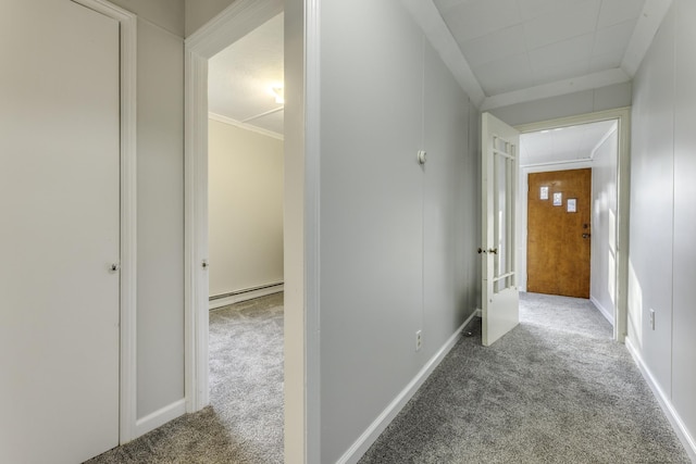 hall with a baseboard radiator, attic access, ornamental molding, and carpet flooring