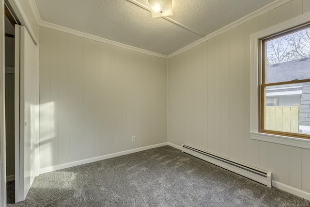 spare room with dark colored carpet, a baseboard heating unit, ornamental molding, a textured ceiling, and baseboards