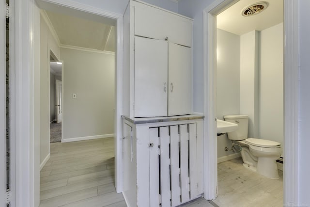 bathroom featuring toilet, crown molding, visible vents, and wood finished floors