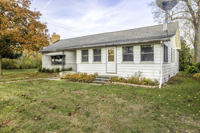 ranch-style house with roof with shingles, a chimney, and a front yard