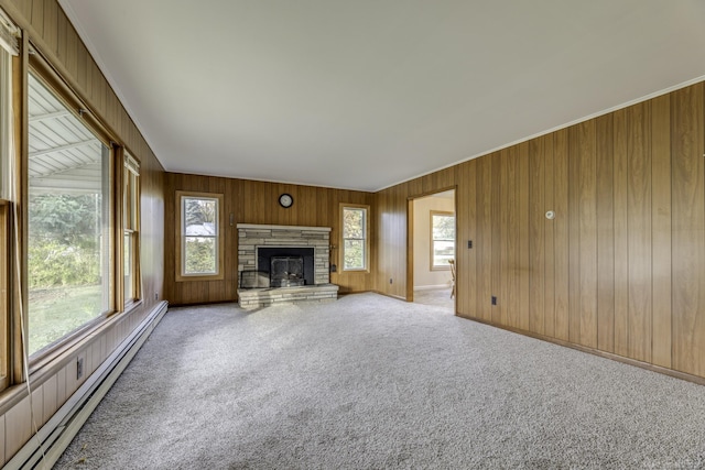 unfurnished living room with wooden walls, a baseboard radiator, a fireplace, and carpet flooring