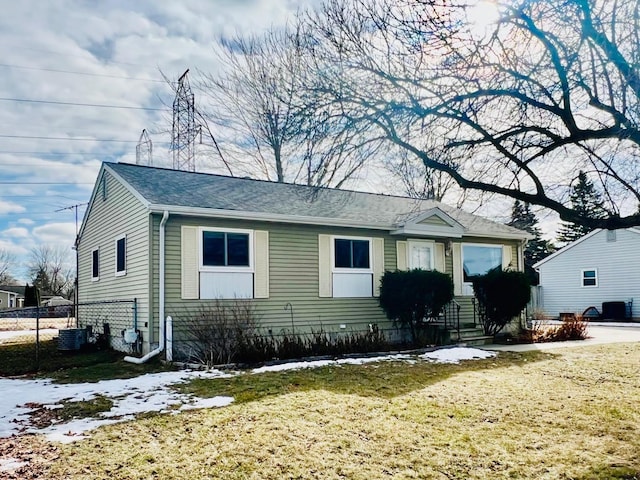 view of front of home with fence, a front lawn, and cooling unit