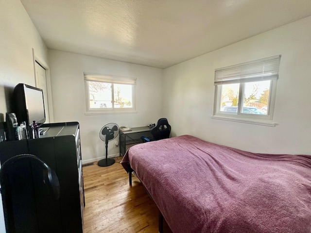 bedroom featuring light wood-style flooring, multiple windows, and baseboards