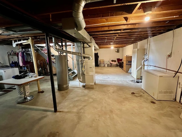 unfinished below grade area featuring refrigerator, gas water heater, independent washer and dryer, and heating unit