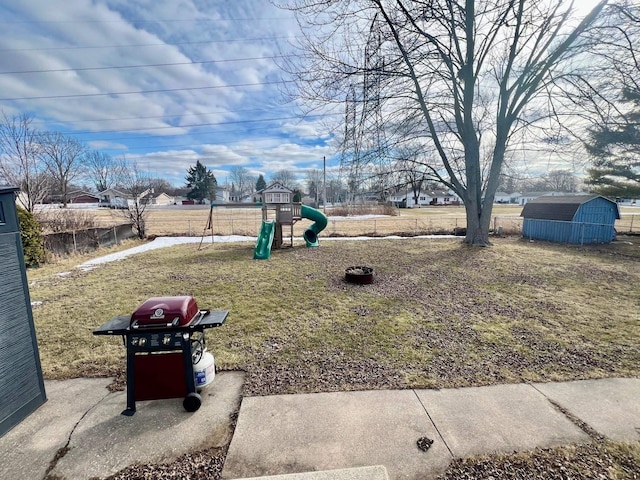 view of yard featuring an outbuilding, a playground, fence, and a shed