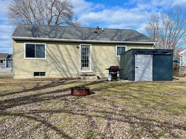 rear view of property with an outbuilding, a shingled roof, a lawn, entry steps, and fence