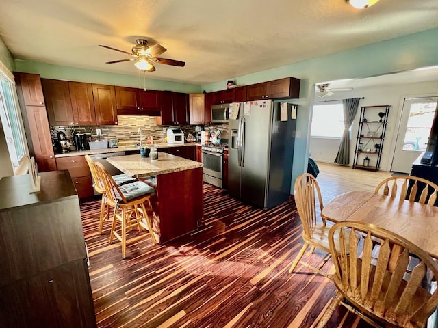 kitchen featuring ceiling fan, stainless steel appliances, dark wood-style flooring, and light countertops