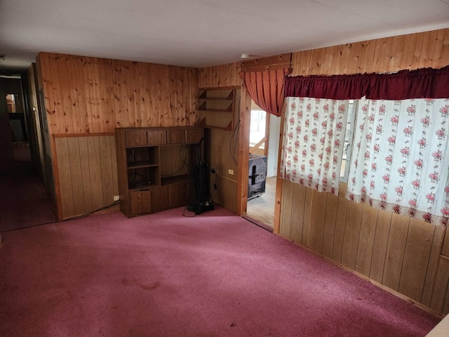 carpeted spare room with wooden walls