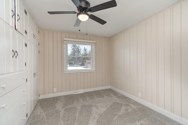 spare room with light colored carpet, ceiling fan, and baseboards