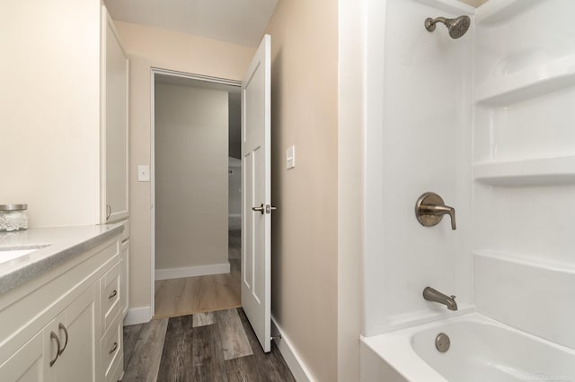 bathroom with shower / bathing tub combination, vanity, baseboards, and wood finished floors