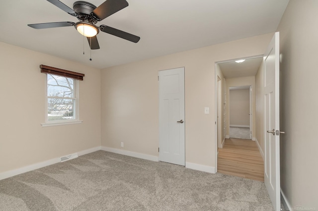 unfurnished bedroom featuring light carpet, ceiling fan, visible vents, and baseboards