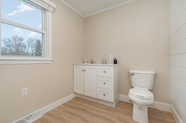 bathroom featuring toilet, wood finished floors, visible vents, baseboards, and crown molding