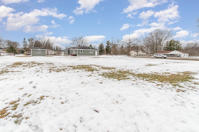 yard covered in snow with an outdoor structure, a detached garage, and a storage unit