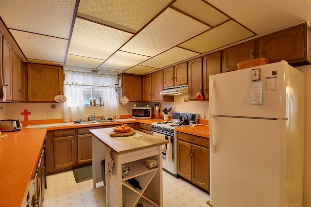 kitchen with white appliances, under cabinet range hood, wood counters, and light floors