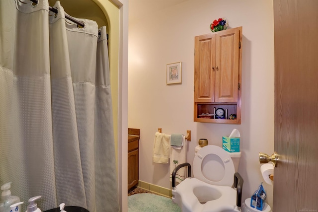 bathroom featuring curtained shower, baseboards, and toilet