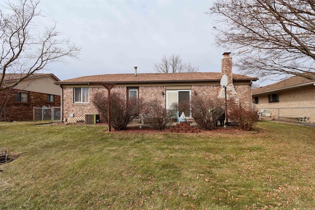 rear view of property featuring fence, a lawn, and brick siding