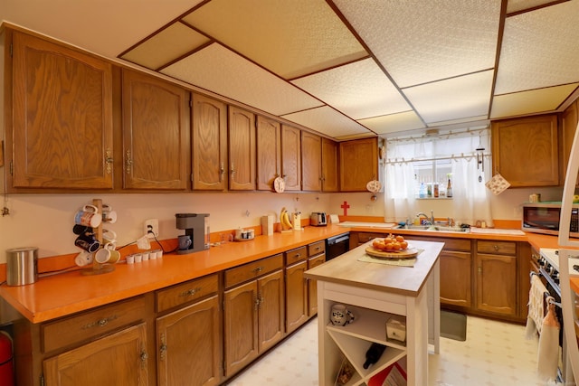 kitchen featuring light floors, stainless steel microwave, range, and brown cabinetry