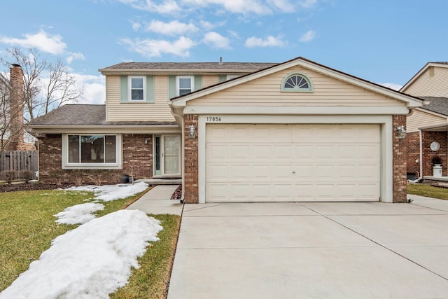 traditional home with driveway, an attached garage, fence, a front lawn, and brick siding