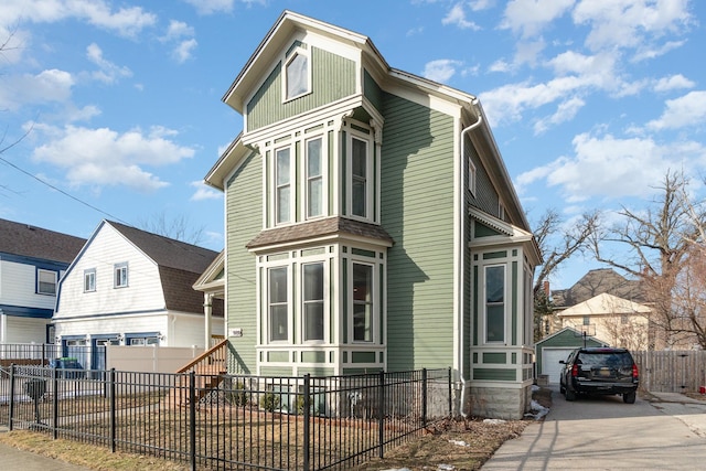 view of front of house with a fenced front yard, an outbuilding, and driveway