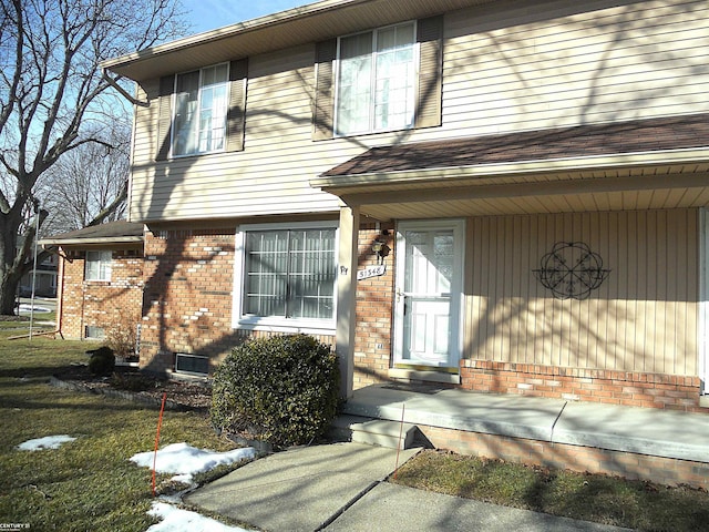 property entrance featuring a shingled roof and brick siding