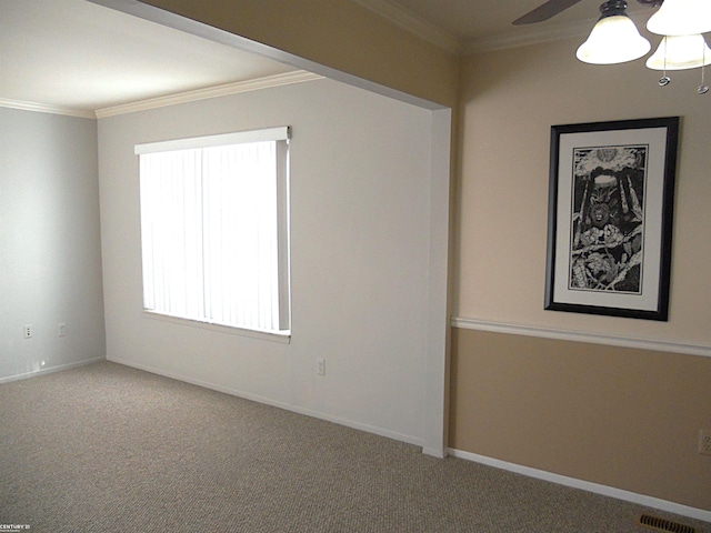 carpeted spare room featuring ornamental molding, visible vents, ceiling fan, and baseboards