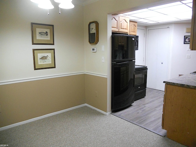 kitchen featuring dark countertops, black appliances, baseboards, and light colored carpet