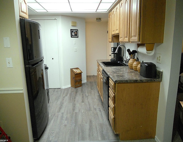 kitchen with dishwasher, dark countertops, light wood-style flooring, freestanding refrigerator, and a sink