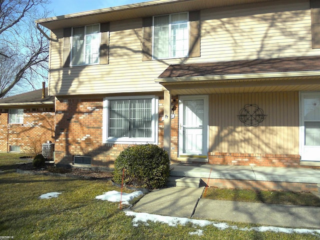 property entrance with a lawn and brick siding