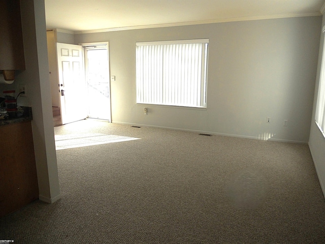 carpeted spare room featuring plenty of natural light, baseboards, and crown molding