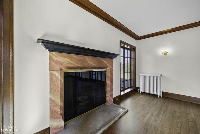 unfurnished living room with a fireplace, radiator heating unit, ornamental molding, wood finished floors, and baseboards