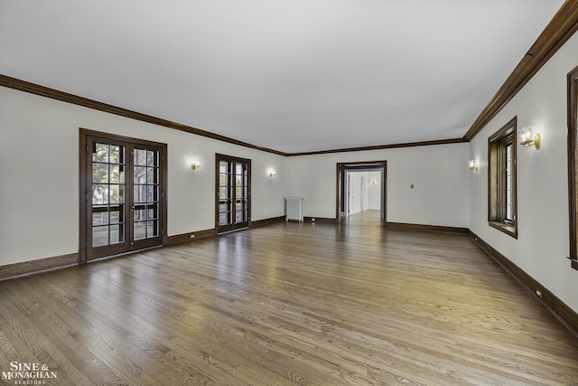 unfurnished living room with radiator, light wood finished floors, baseboards, and french doors