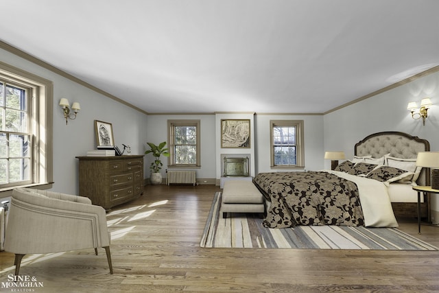 bedroom featuring radiator, crown molding, a fireplace, and wood finished floors