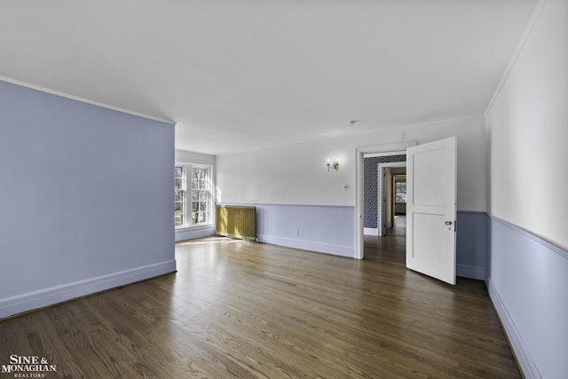 spare room featuring baseboards, wood finished floors, and ornamental molding