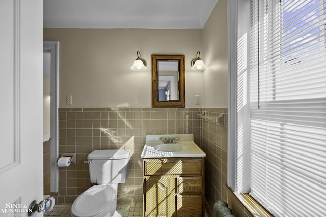 bathroom featuring toilet, wainscoting, tile walls, and vanity