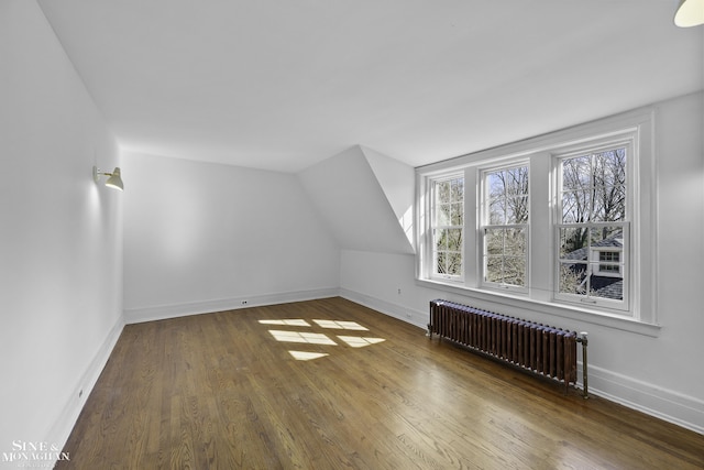 bonus room with radiator heating unit, wood finished floors, and baseboards