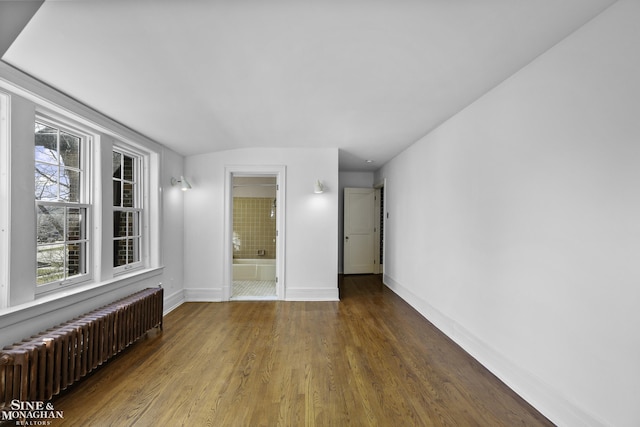 unfurnished room with baseboards, wood finished floors, a wealth of natural light, and radiator