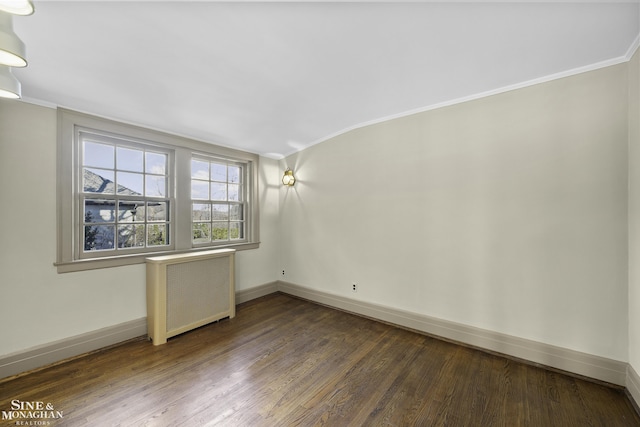 spare room with baseboards, radiator, wood finished floors, vaulted ceiling, and crown molding