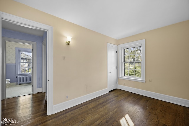 spare room featuring radiator, baseboards, and dark wood-style flooring