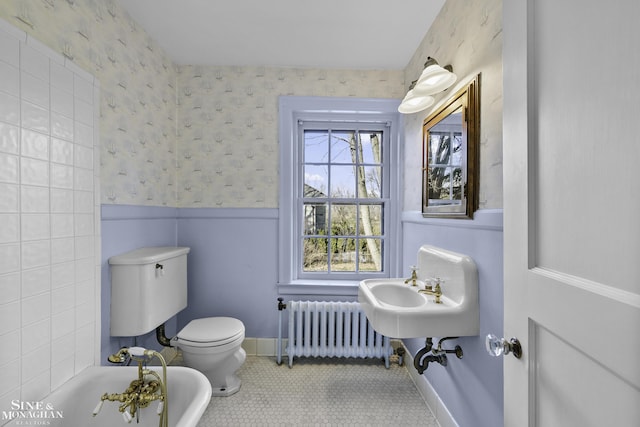 full bath with radiator, a wainscoted wall, a bathing tub, and wallpapered walls