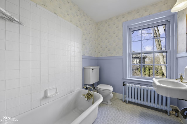 full bathroom with a wainscoted wall, radiator, a freestanding bath, and wallpapered walls