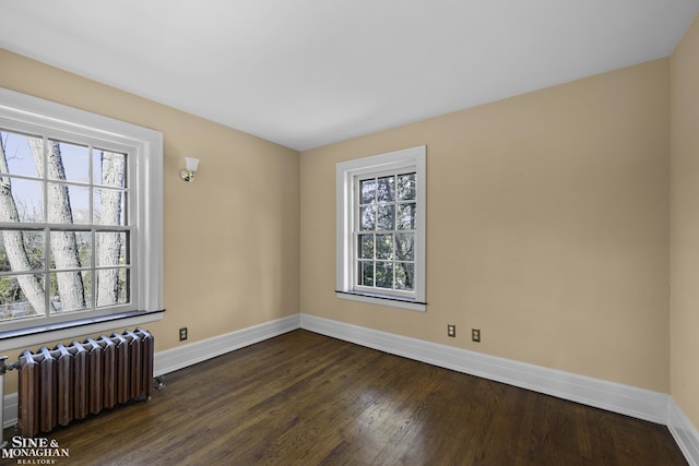 empty room featuring radiator, plenty of natural light, and baseboards