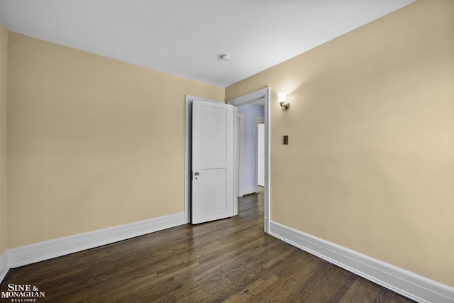 unfurnished room featuring baseboards and dark wood finished floors