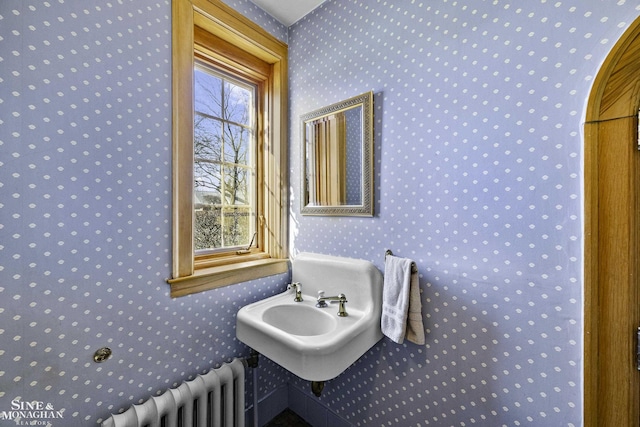 bathroom featuring wallpapered walls, radiator heating unit, and a sink