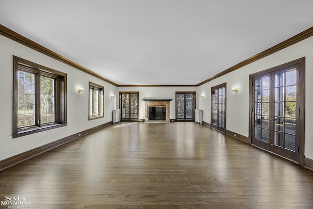 unfurnished living room with french doors, a wealth of natural light, radiator, a high end fireplace, and wood finished floors