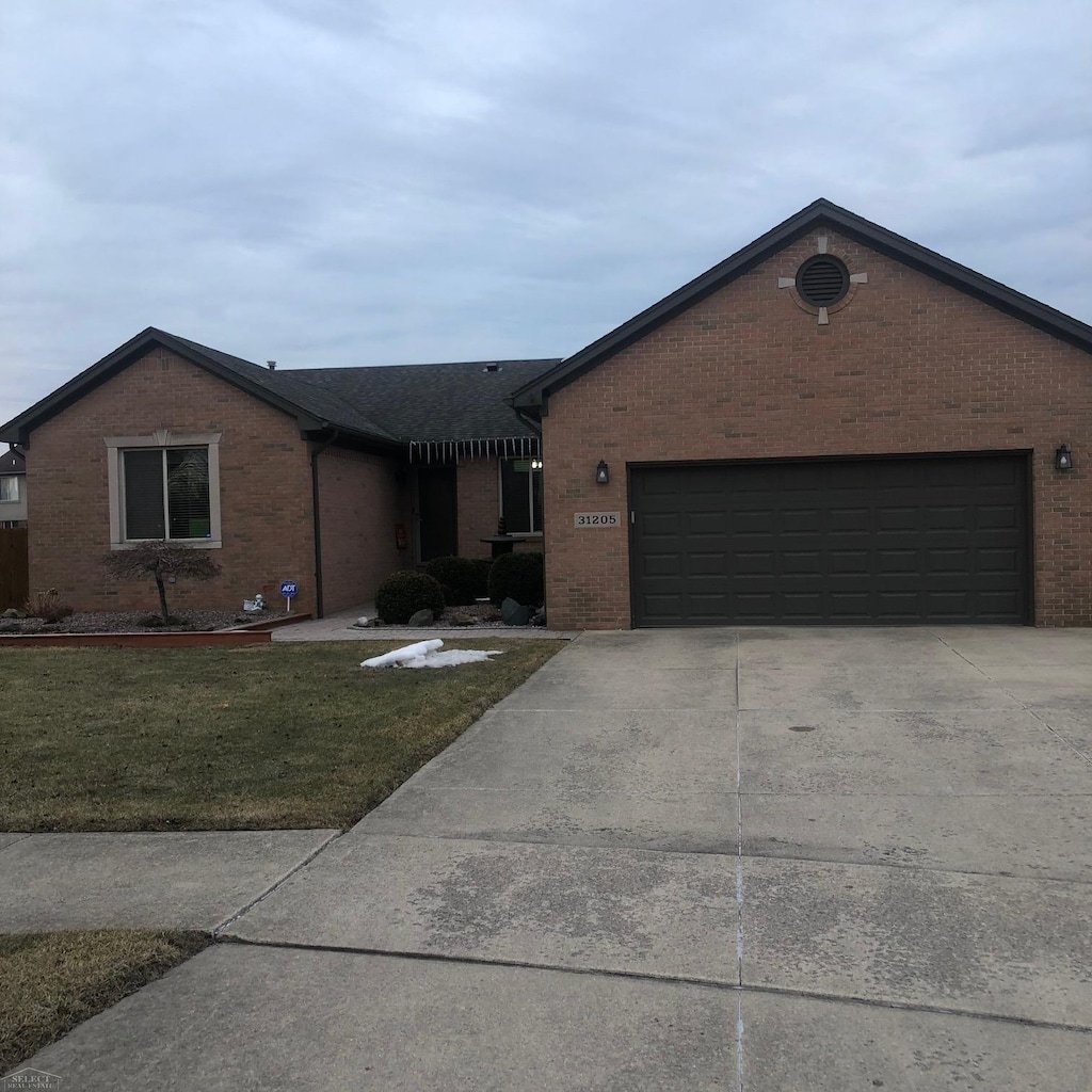 single story home featuring an attached garage, a front lawn, concrete driveway, and brick siding