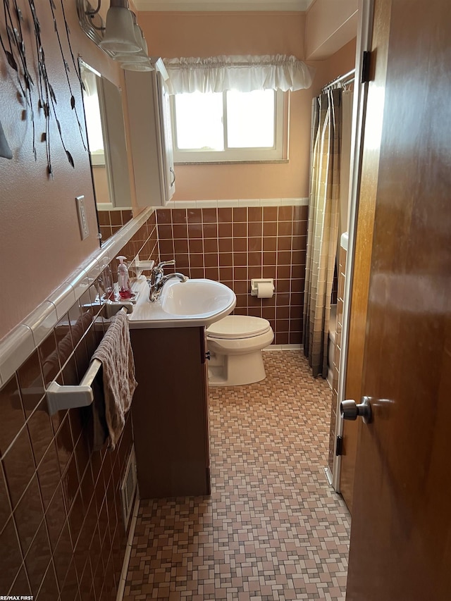 bathroom featuring a wainscoted wall, tile walls, visible vents, toilet, and vanity