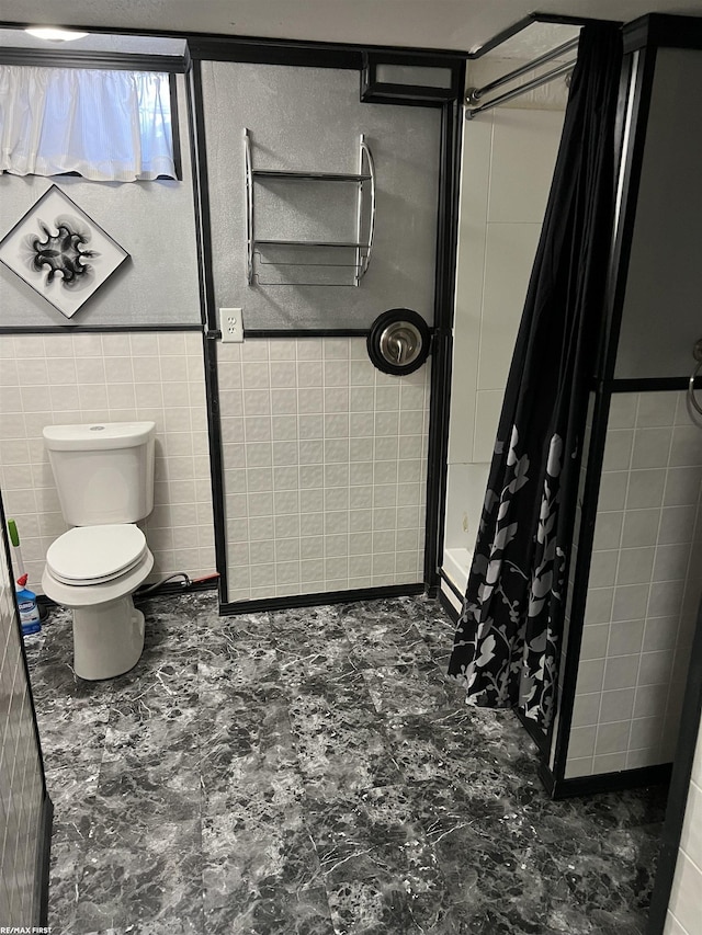 bathroom featuring toilet, a stall shower, and tile walls