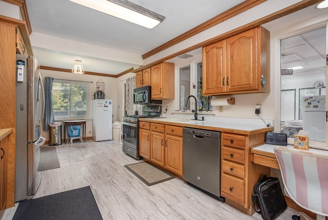 kitchen featuring a sink, light wood-style floors, light countertops, ornamental molding, and appliances with stainless steel finishes